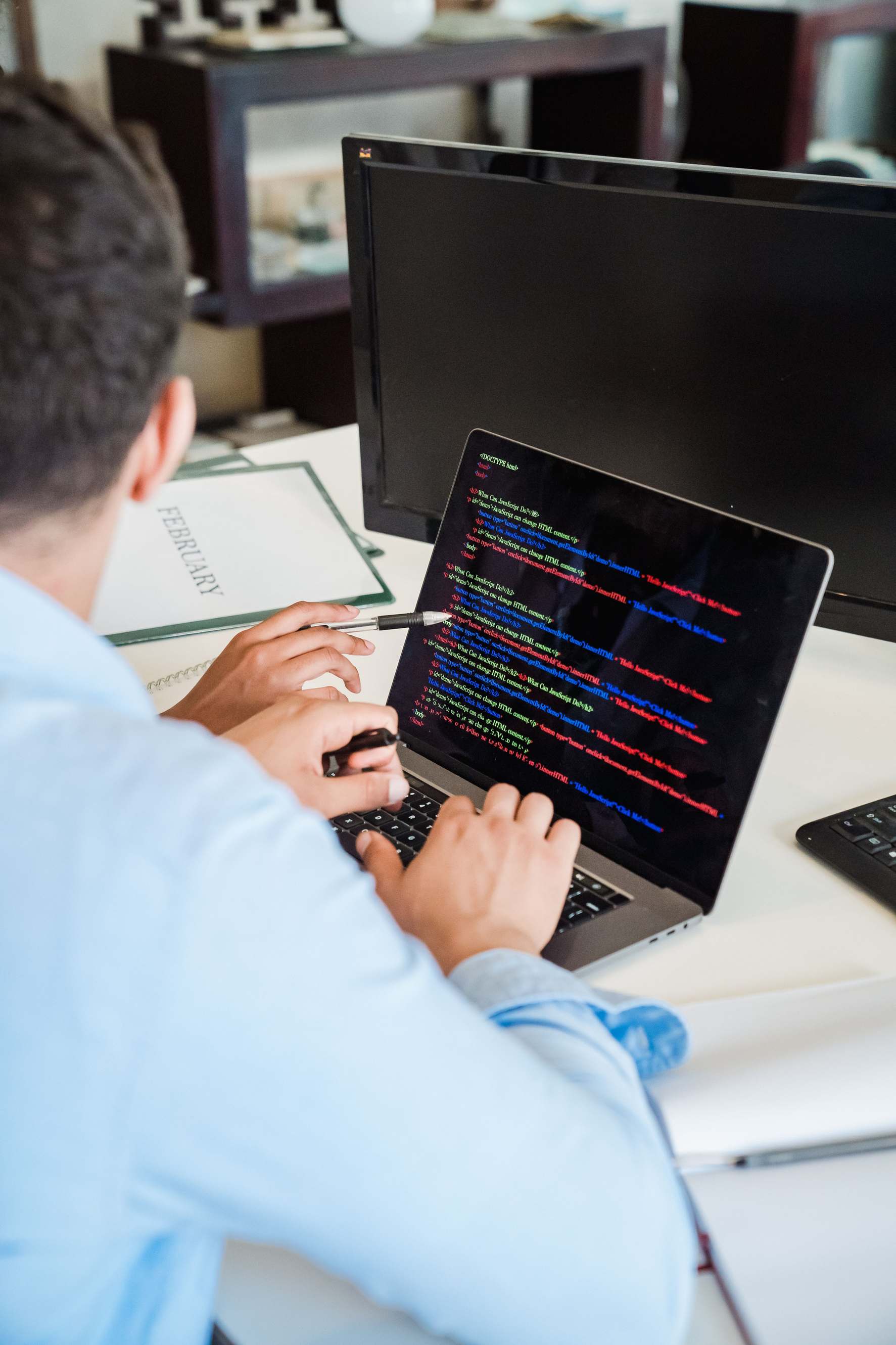 Developer workspace with laptop showing software development, office worker typing code